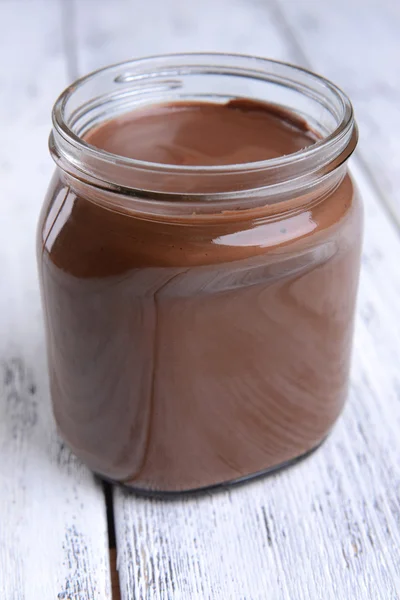 Сладкий шоколадный крем в банке на столе крупным планом — стоковое фото