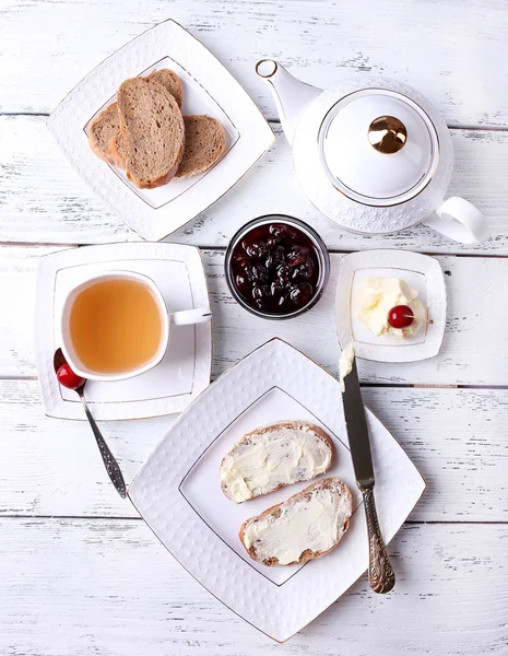 Vers brood met cherry jam en zelfgemaakte boter op plaat op houten achtergrond — Stockfoto