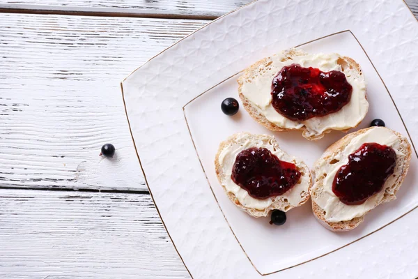 Pane fresco con burro fatto in casa e marmellata di ribes nero su sfondo di legno — Foto Stock