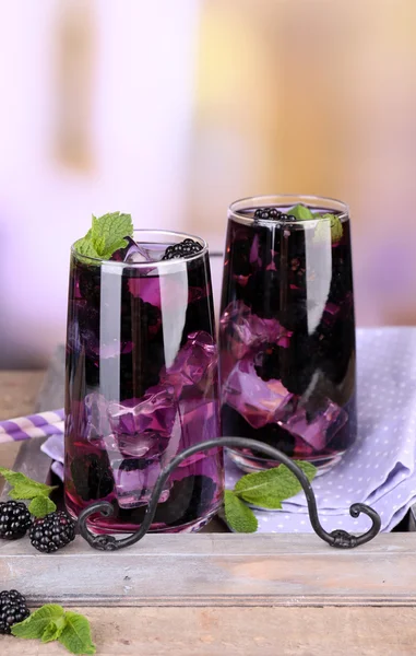 Tasty cool blackberry lemonade with ice on wooden table, on light background — Stock Photo, Image