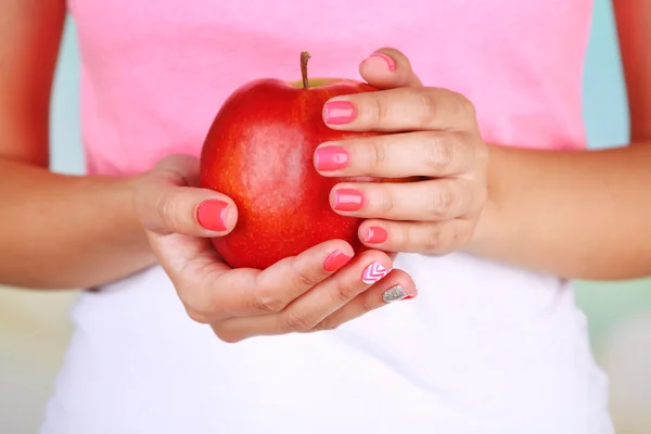 Női kéz elegáns színes körmök gazdaságot, piros alma, közeli, színes háttérrel — Stock Fotó