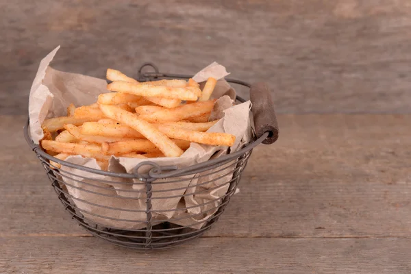 Batatas fritas saborosas em cesta de metal na mesa de madeira — Fotografia de Stock