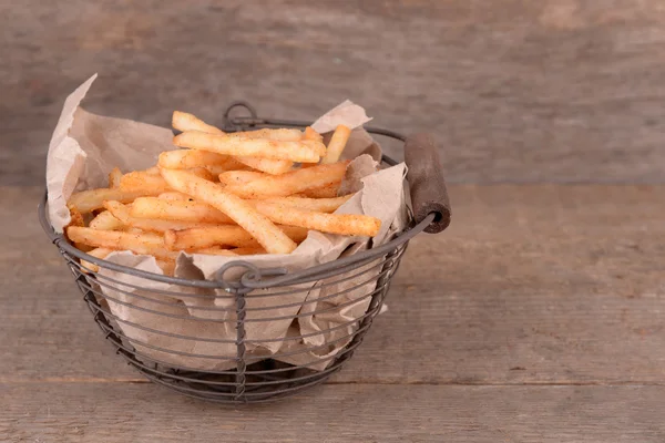 Sabrosas papas fritas en canasta de metal sobre mesa de madera —  Fotos de Stock