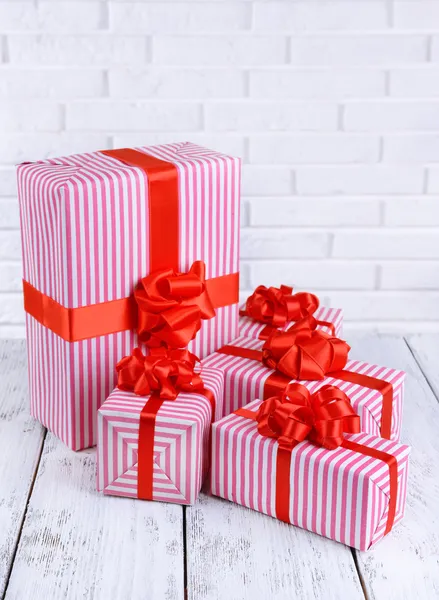 Prachtige geschenken op tafel op bakstenen muur achtergrond — Stockfoto