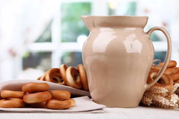 Jar of milk, tasty bagels and spikelets on table — Stock Photo, Image