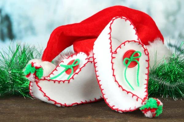 Decorative Christmas shoes with Santa hat on table on bright background — Stock Photo, Image