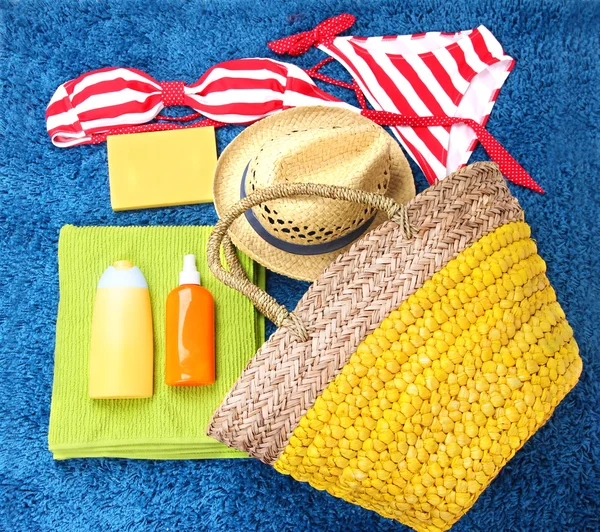 Rieten tas, badpak, flessen met lotions op kleur achtergrond. — Stockfoto