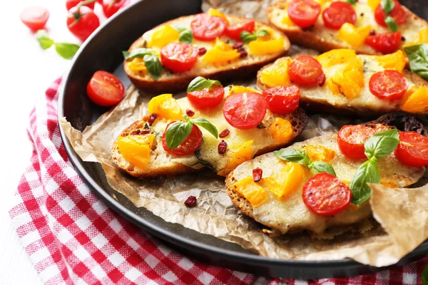 Sabroso bruschetta con tomates en la cacerola, sobre la mesa — Foto de Stock