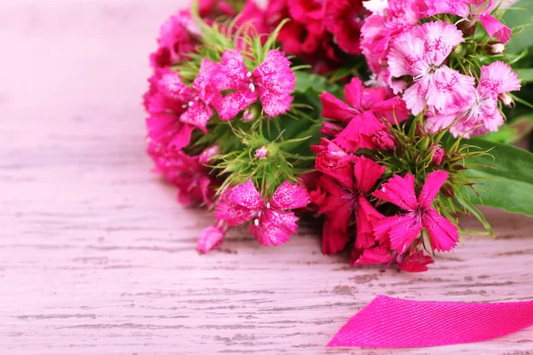 Beautiful bouquet with ribbon on wooden background — Stock Photo, Image