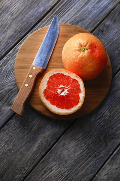Dojrzałe grejpfrutów i nóż na deski do krojenia, na tle drewniane — Zdjęcie stockowe