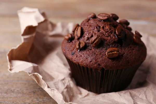 Muffin al cioccolato e chicchi di caffè su carta, su fondo di legno — Foto Stock