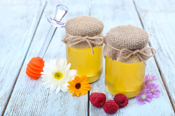 Frasco cheio de deliciosos mel fresco e flores silvestres na mesa de madeira — Fotografia de Stock
