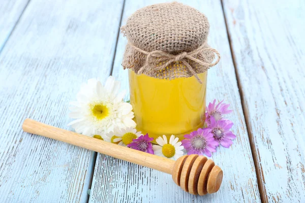 Pot plein de délicieux miel frais et de fleurs sauvages sur une table en bois — Photo