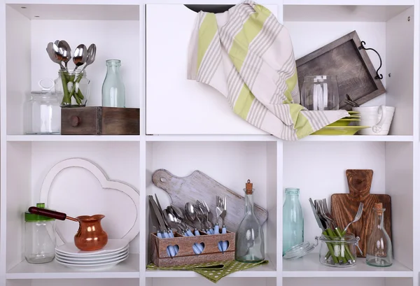 Kitchen utensils and tableware on beautiful white shelves — Stock Photo, Image