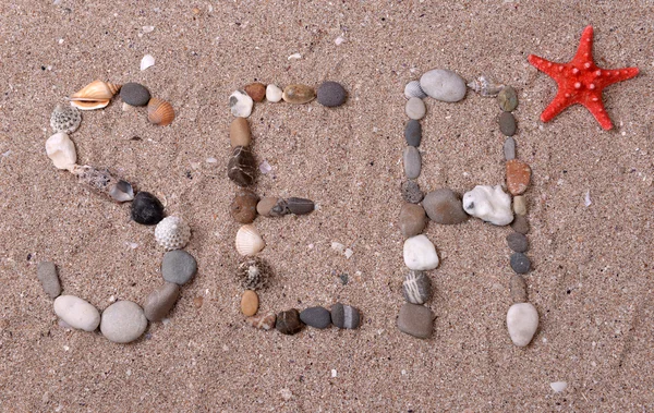 Słowo morza wykonane z muszli i kamienie na piasku — Zdjęcie stockowe