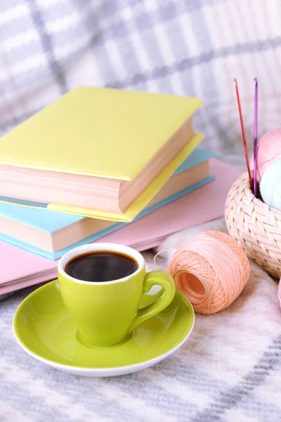 Kopje koffie en garen voor breien op plaid met boeken close-up — Stockfoto