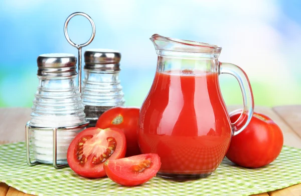 Jugo de tomate en jarra de vidrio, sobre mesa de madera, sobre fondo brillante —  Fotos de Stock