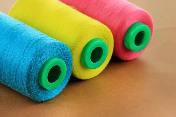 Colored bobbins on brown background — Stock Photo, Image