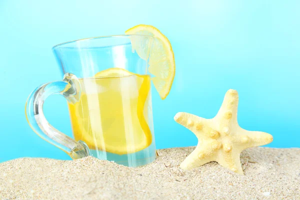 Cold tea in sand on blue background — Stock Photo, Image