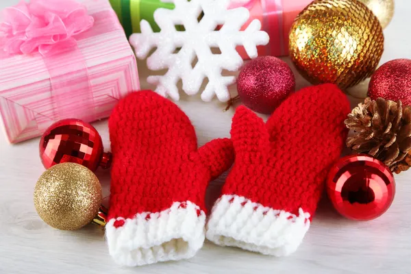 Červená zimní palčáky s vánoční hračky na dřevěný stůl — Stock fotografie
