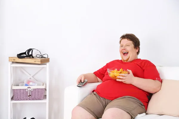 Hombre perezoso con sobrepeso sentado en el sofá y viendo la televisión — Foto de Stock