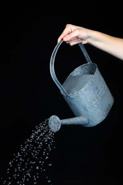 Water pouring from watering can on black background — Stock Photo, Image