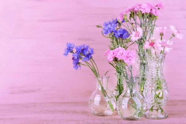 Prachtige zomerbloemen in vazen op roze houten achtergrond — Stockfoto