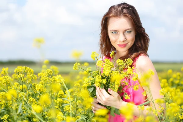 Hermosa joven en el campo de flores — Foto de Stock