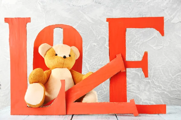Decoratieve brieven vormen woord Love met teddybeer op grijze achtergrond — Stockfoto