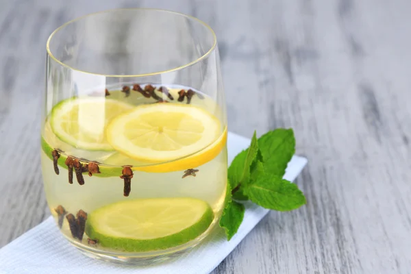 Fresh summer drink with lime and cloves in glass, on color wooden background — Stock Photo, Image