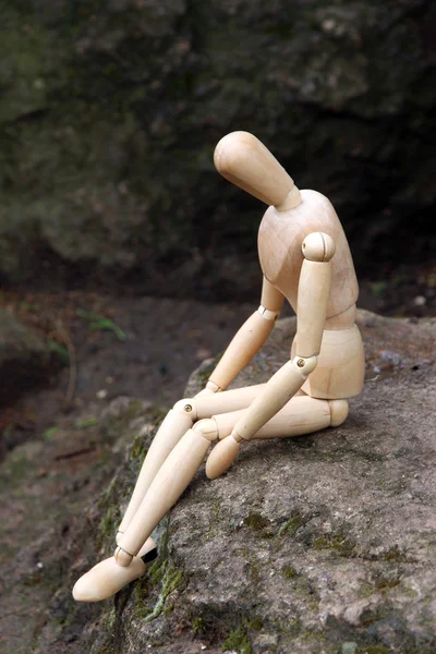 Títere de pose de madera sentado en piedra, al aire libre —  Fotos de Stock