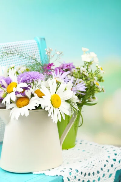 Buquê de flores coloridas em baldes decorativos, na cadeira, no fundo brilhante — Fotografia de Stock