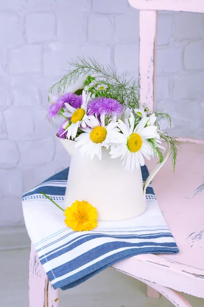 Bouquet de fleurs colorées dans une cruche décorative, sur chaise, sur fond intérieur de la maison — Photo