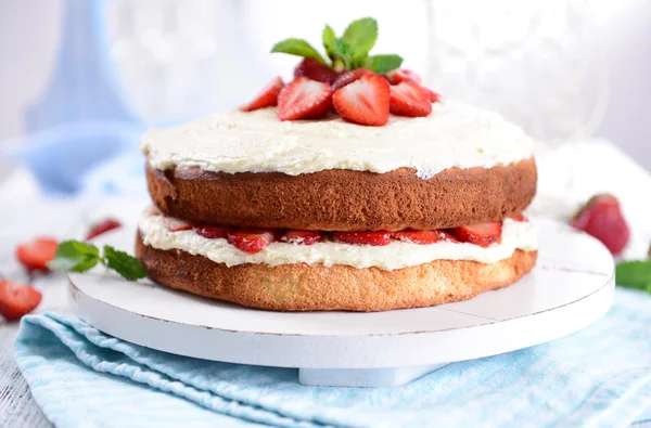 Heerlijke biscuit cake met aardbeien op tafel op lichte achtergrond — Stockfoto