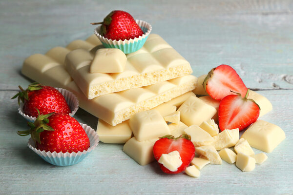 White chocolate bar with fresh strawberries, on color wooden background