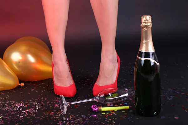 Jambes avec confettis, champagne et ballons sur le sol — Photo