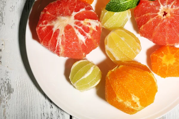 Citrus fruits without skin, on plate, on wooden background — Stock Photo, Image