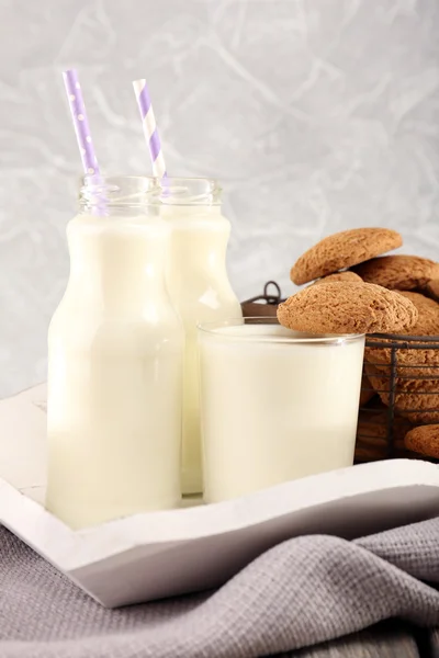 Mleko i ciasteczka na stole na światło szary tło — Zdjęcie stockowe