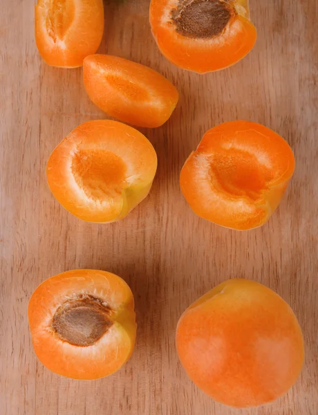 Ripe apricots with green mint leaves on cutting board, on wooden background — Stock Photo, Image