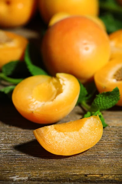 Zralé meruňky s mátově zelené listy na dřevěné pozadí — Stock fotografie