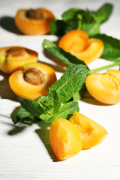 Ripe apricots with green mint leaves on wooden background — Stock Photo, Image