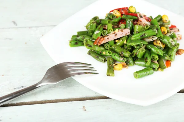 Salade avec haricots verts, jambon et maïs sur assiette, sur fond de bois couleur — Photo