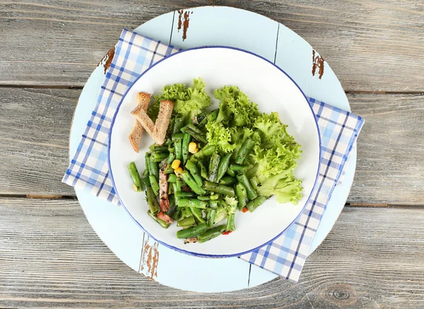 Salad with green beans, ham and  corn on plate, on color wooden background — Stock Photo, Image