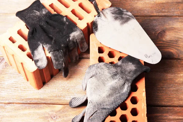 Guantes y ladrillos de tela usados sucios sobre fondo de madera — Foto de Stock