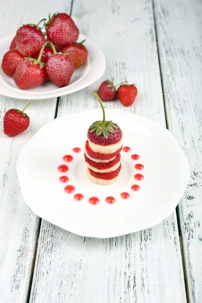 Fresh strawberry with banana on skewers on plate on table close-up — Stock Photo, Image