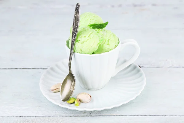 Es krim pistachio lezat dalam cangkir di atas meja kayu — Stok Foto