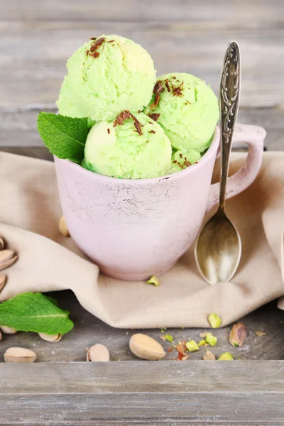 Smaczne lody pistacjowe Cup na drewnianym stole — Zdjęcie stockowe