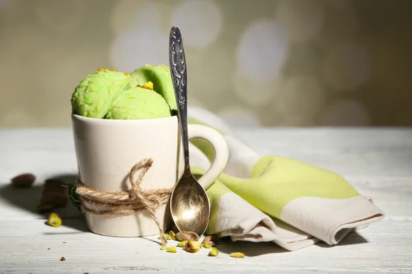 Es krim pistachio lezat dalam cangkir di atas meja kayu, pada latar belakang cahaya — Stok Foto