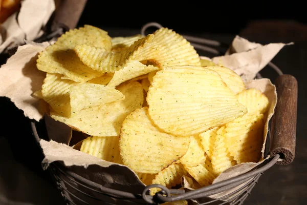 Sabrosas papas fritas en canasta de metal sobre mesa de madera con luz oscura — Foto de Stock