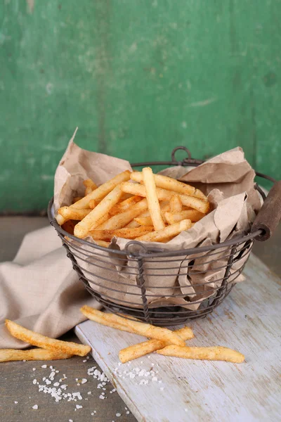 Goda pommes frites i metall korg på bord — Stockfoto